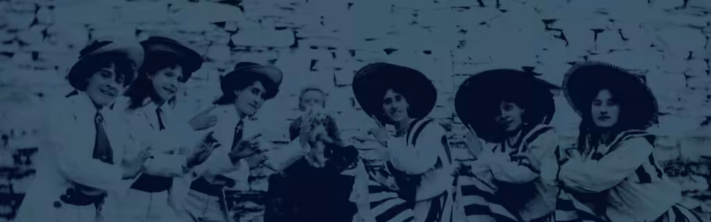A group of women wearing stylish hats gathering in front of a stone wall.