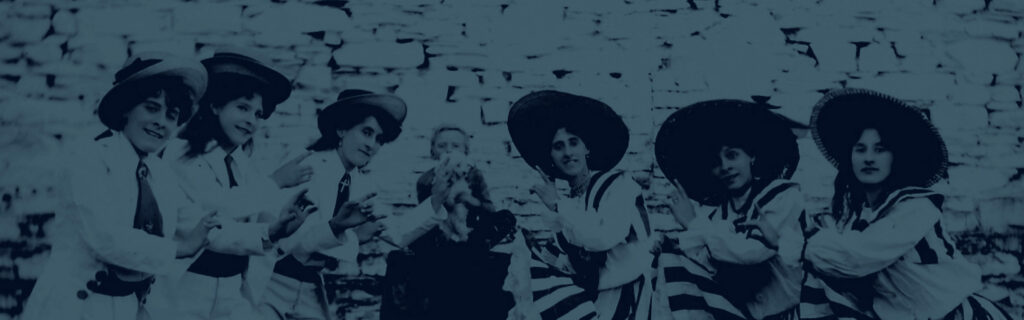 A group of women wearing stylish hats gathering in front of a stone wall.