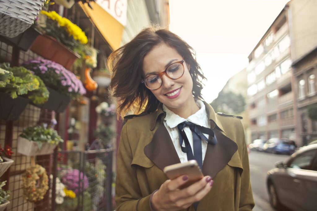 A woman in glasses is browsing her mobile phone.