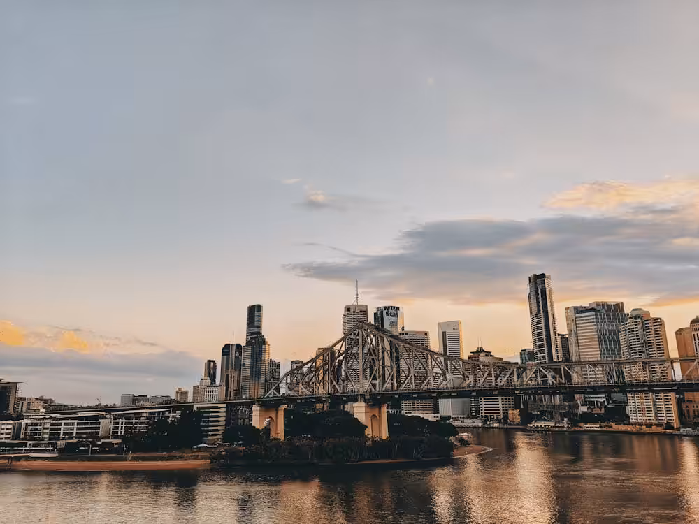 Put Your Customers First: How to Build a Winning Digital Strategy 1 The city skyline at sunset seamlessly intertwines with the steel bridge spanning a river, echoing the precision of a digital strategy. Skyscrapers rise majestically in the background against a partly cloudy sky, creating a harmonious blend of nature and urban planning.