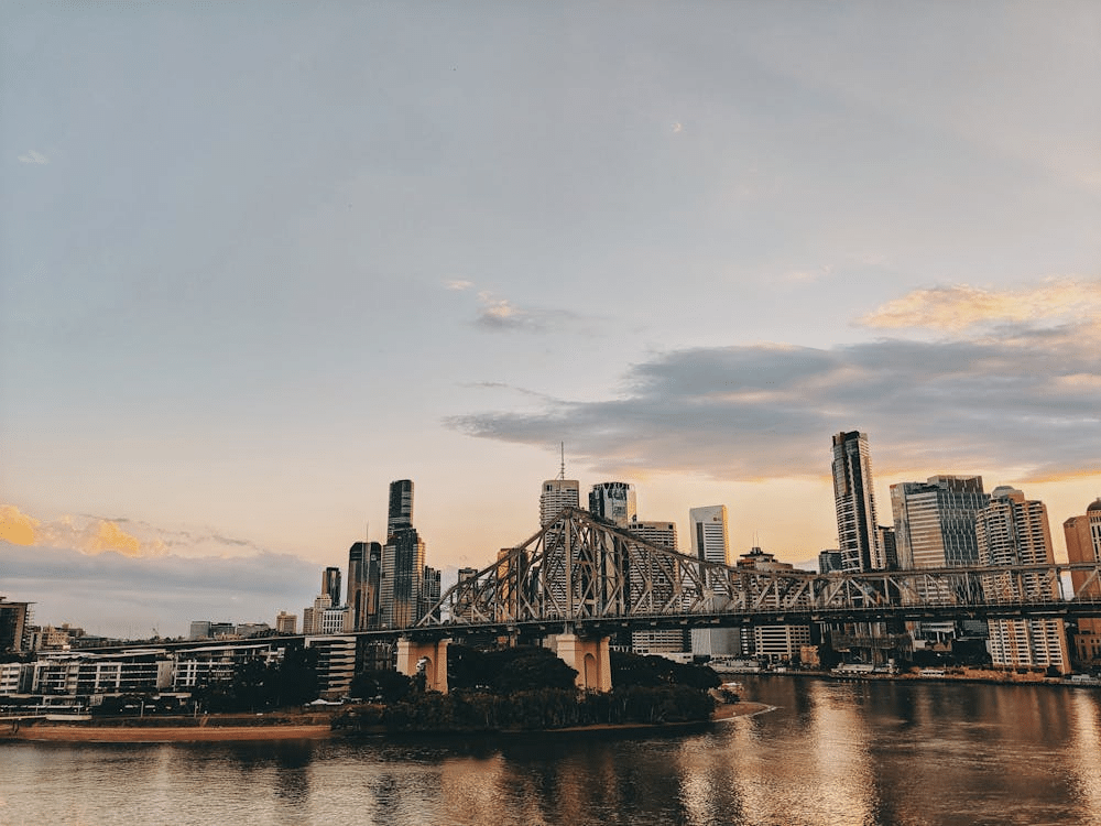 Put Your Customers First: How to Build a Winning Digital Strategy 1 The city skyline at sunset seamlessly intertwines with the steel bridge spanning a river, echoing the precision of a digital strategy. Skyscrapers rise majestically in the background against a partly cloudy sky, creating a harmonious blend of nature and urban planning.